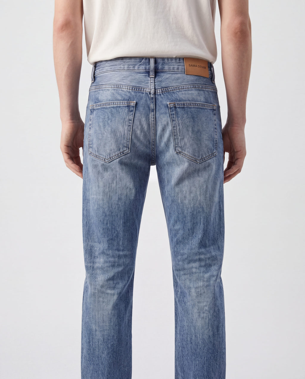 Close-up back detail view of Sama Denim men's light wash slim fit jeans with signature leather patch