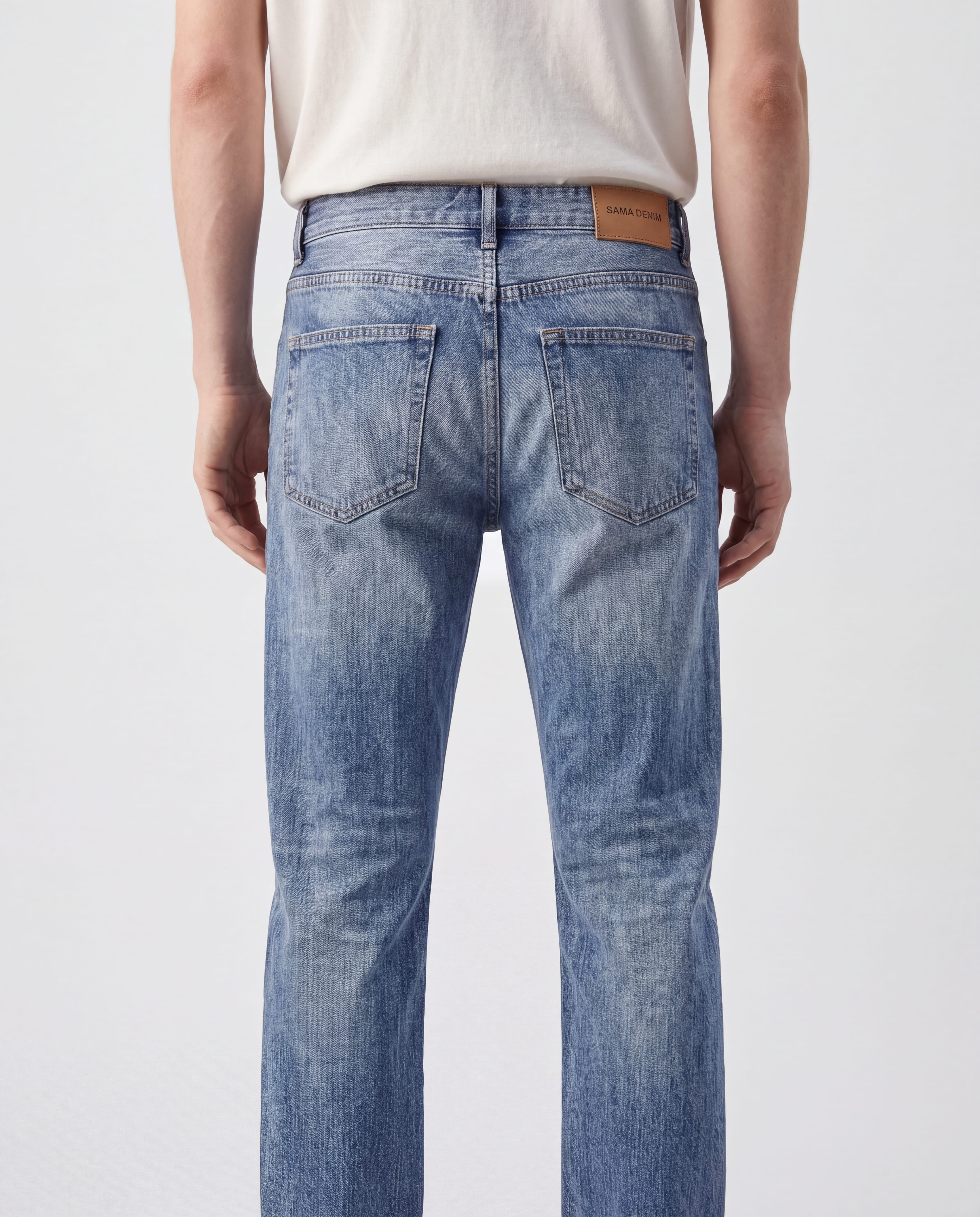Close-up back detail view of Sama Denim men's light wash slim fit jeans with signature leather patch