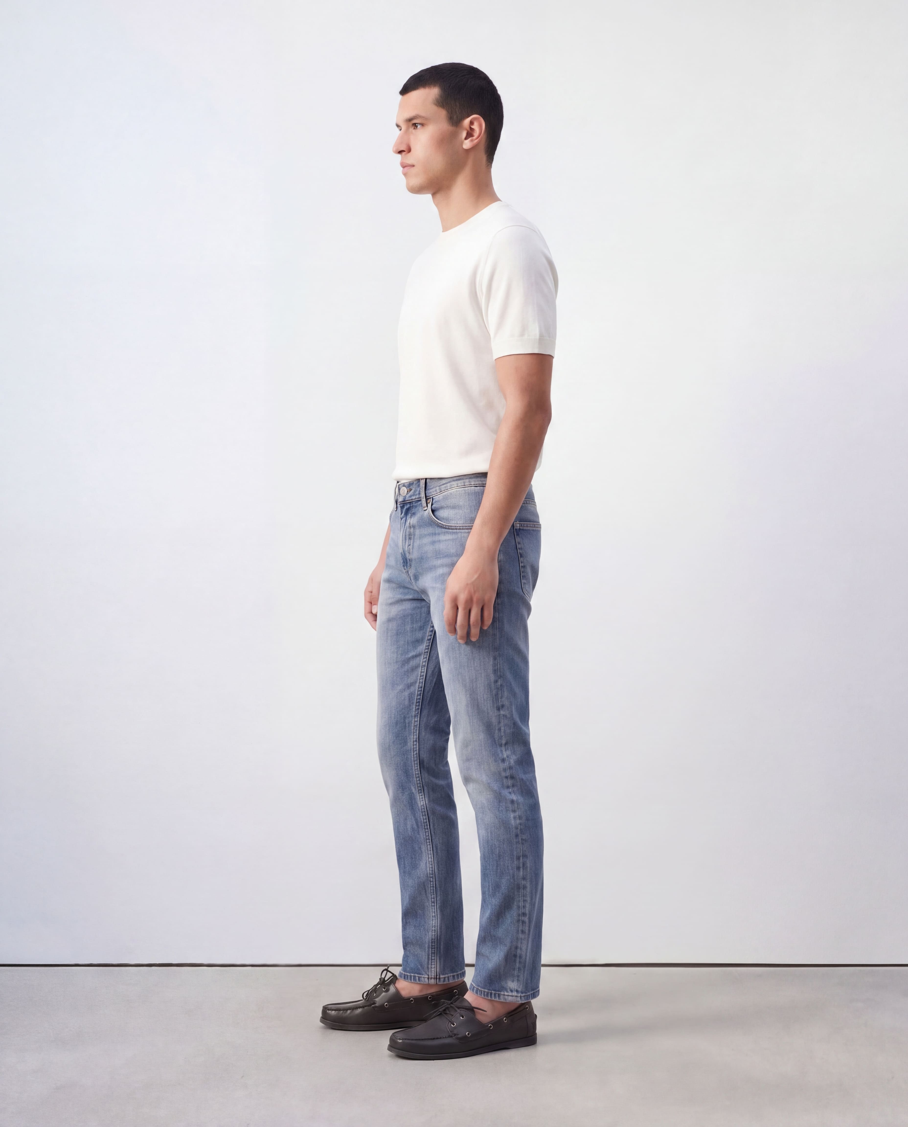 Side profile view of model wearing Sama Denim men's light wash slim fit jeans