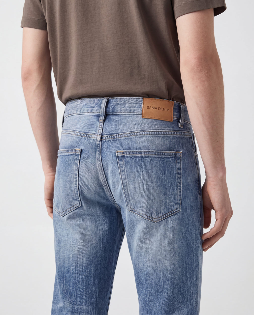 Close-up back detail of Sama Denim men's light wash straight fit jeans with signature leather patch