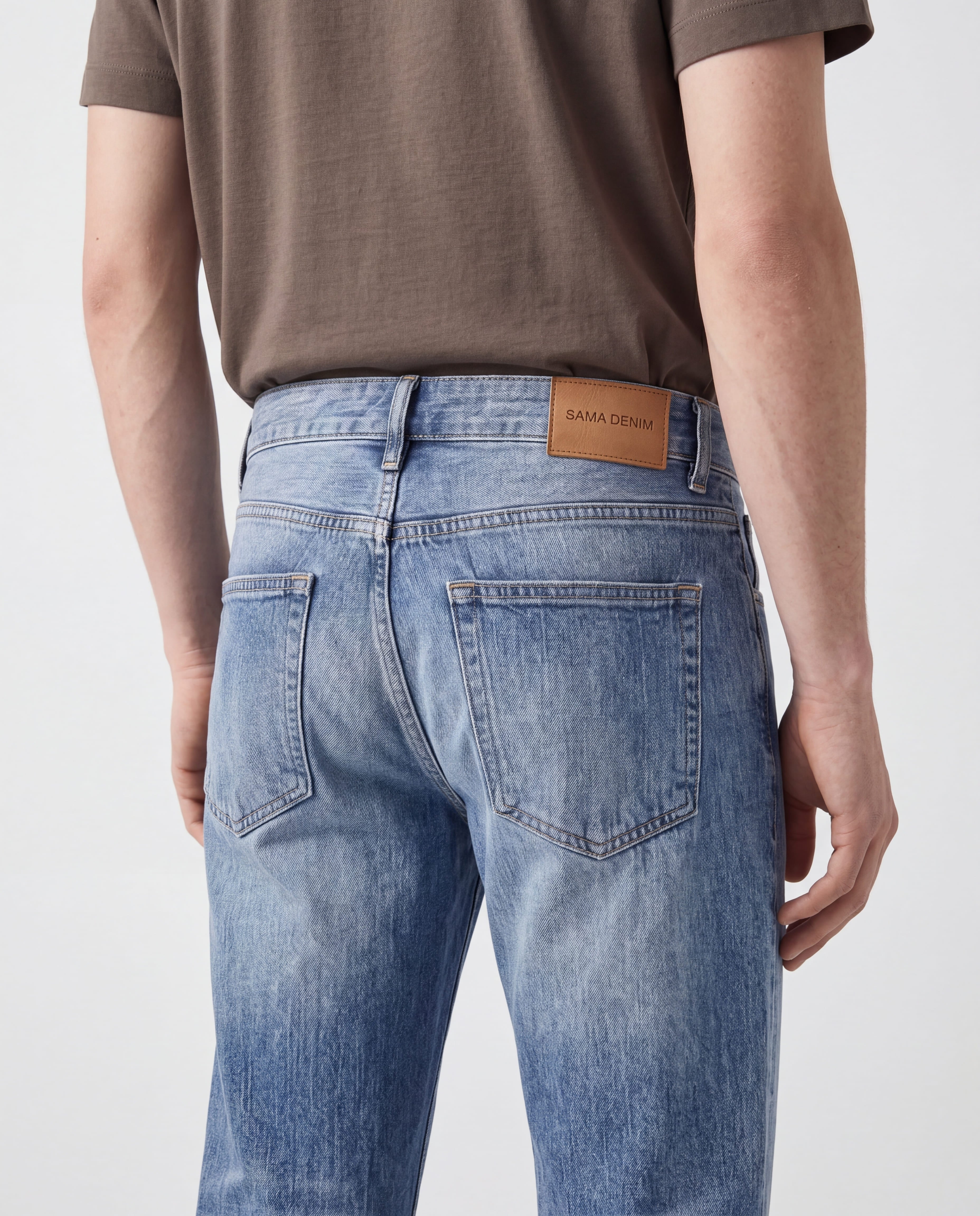 Close-up back detail of Sama Denim men's light wash straight fit jeans with signature leather patch