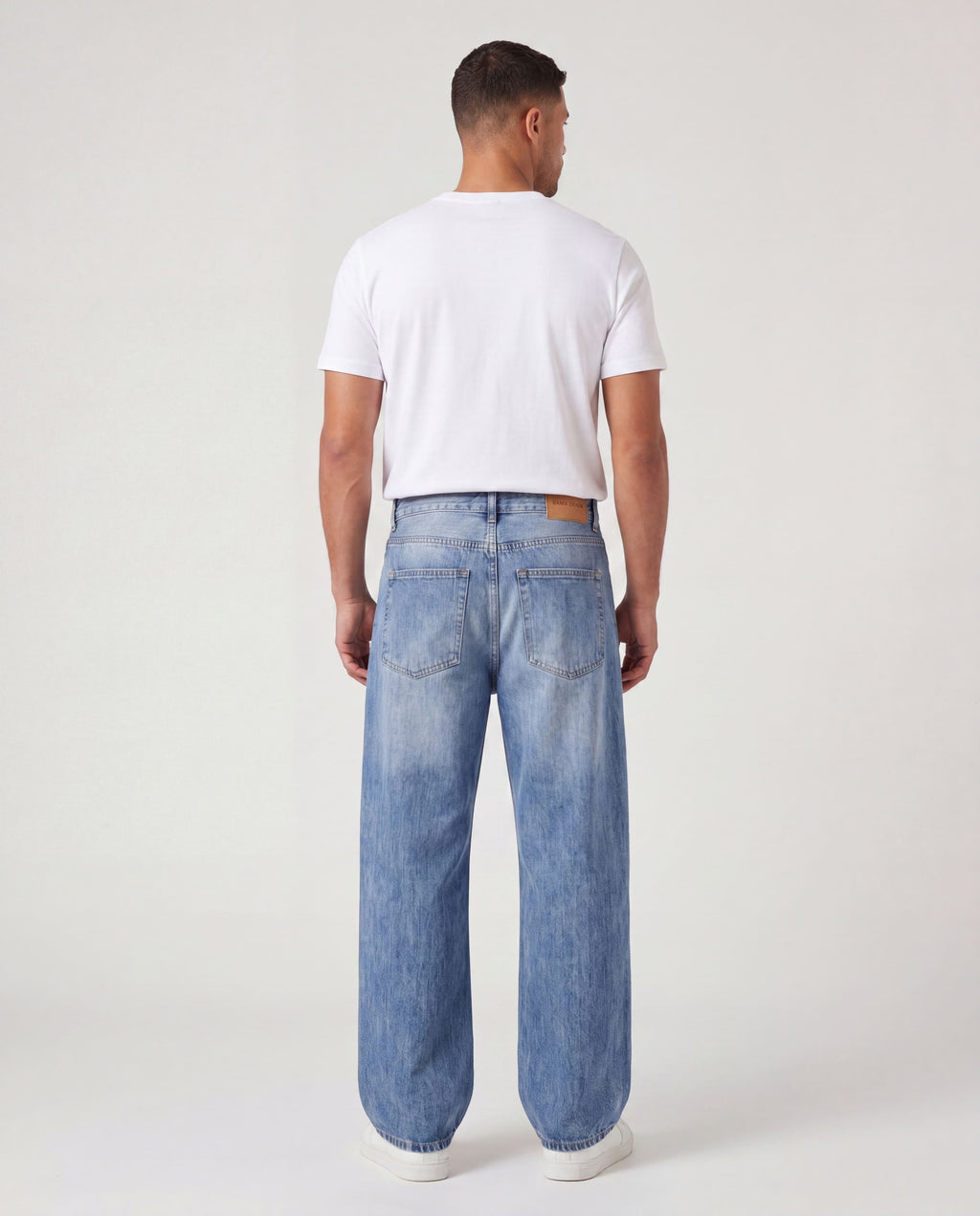 Back view of model wearing Sama Denim men's light wash baggy fit jeans