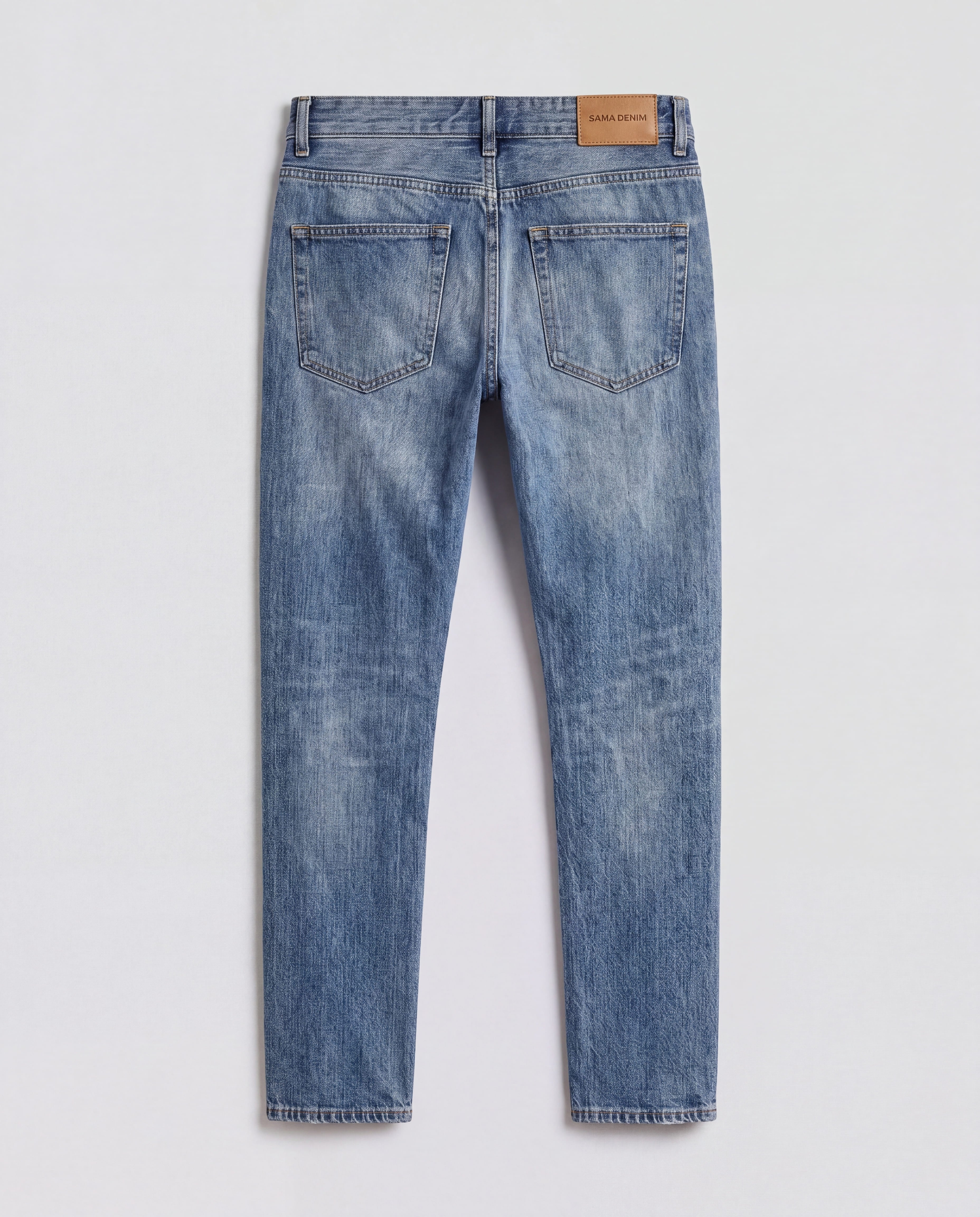 Back flat lay view of Sama Denim men's light wash slim fit jeans with signature leather patch