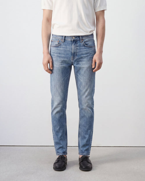 Model wearing Sama Denim men's light wash slim fit jeans front view with minimalist styling