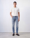 Model wearing Sama Denim men's light wash slim fit jeans with white t-shirt in minimalist studio